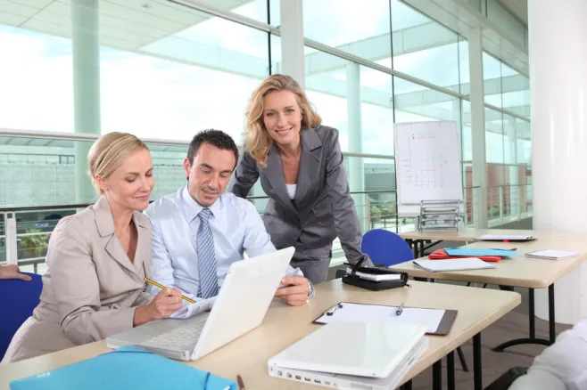 Two female and one male workes looking at lapotop screen in the office