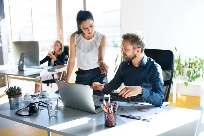 A woman and a man are looking at a laptop